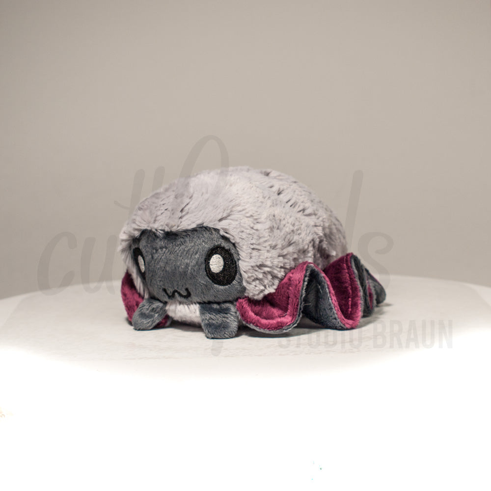 Front view of a cuttlepod plush toy, captured at a slight angle to highlight its charming features: large, cartoonish eyes, ruffled fins, and a cuddly, furry texture.