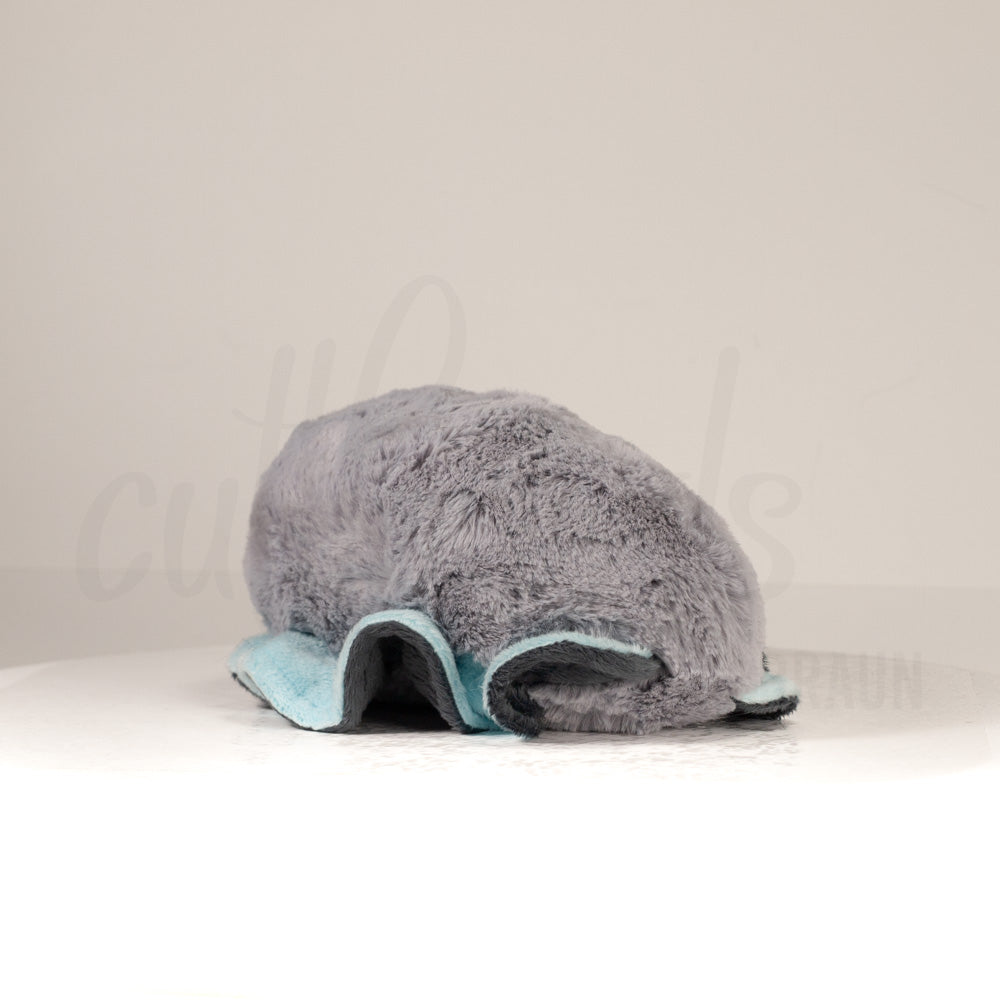 Slightly angled back view of a cuttlepod plush toy, highlighting two-tone ruffled fins, and a cuddly, furry body that comes to a soft point at the rear.