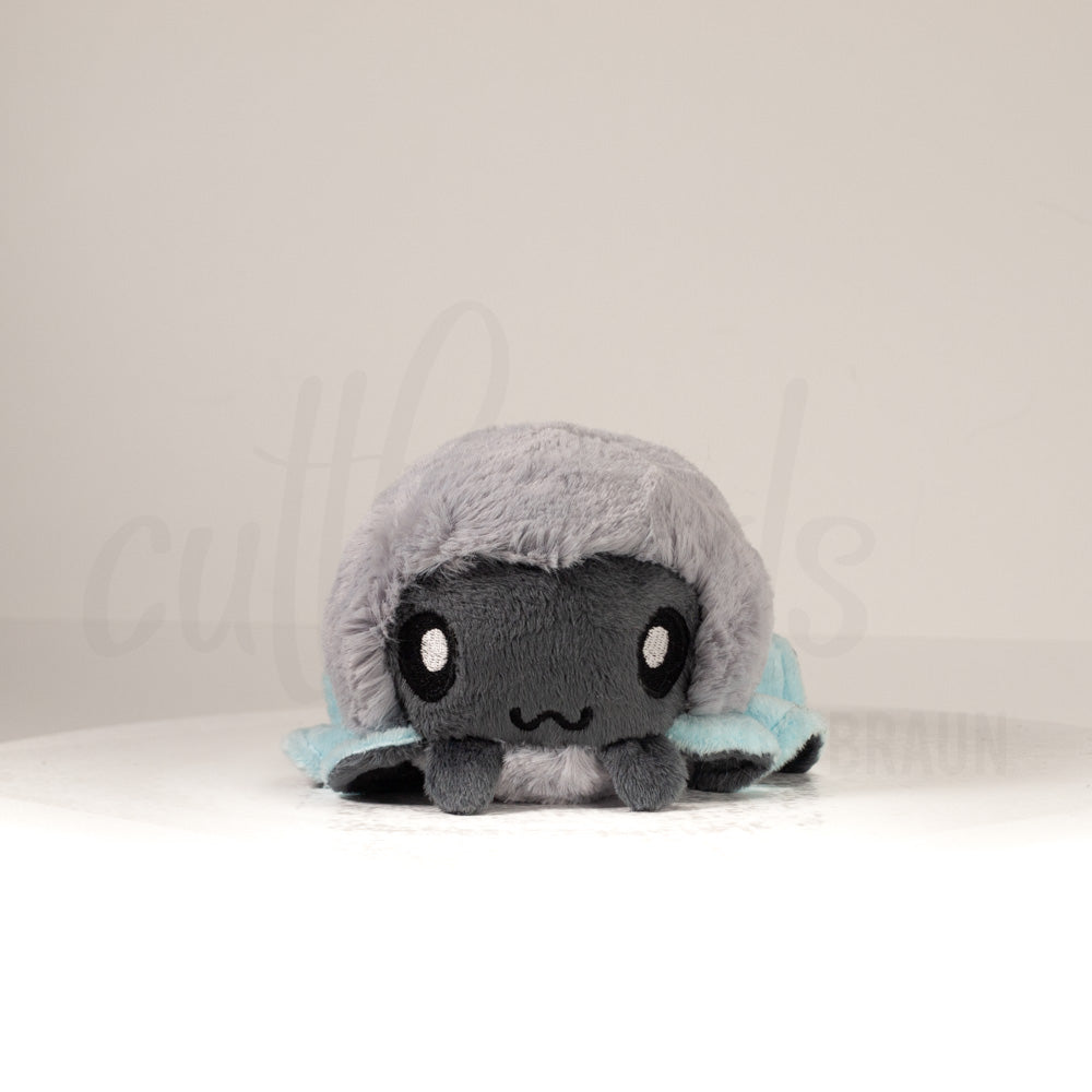 Front view of a cuttlepod plush toy, showcasing its unique form with large, cartoonish eyes, ruffled fins, and a cuddly, furry texture.