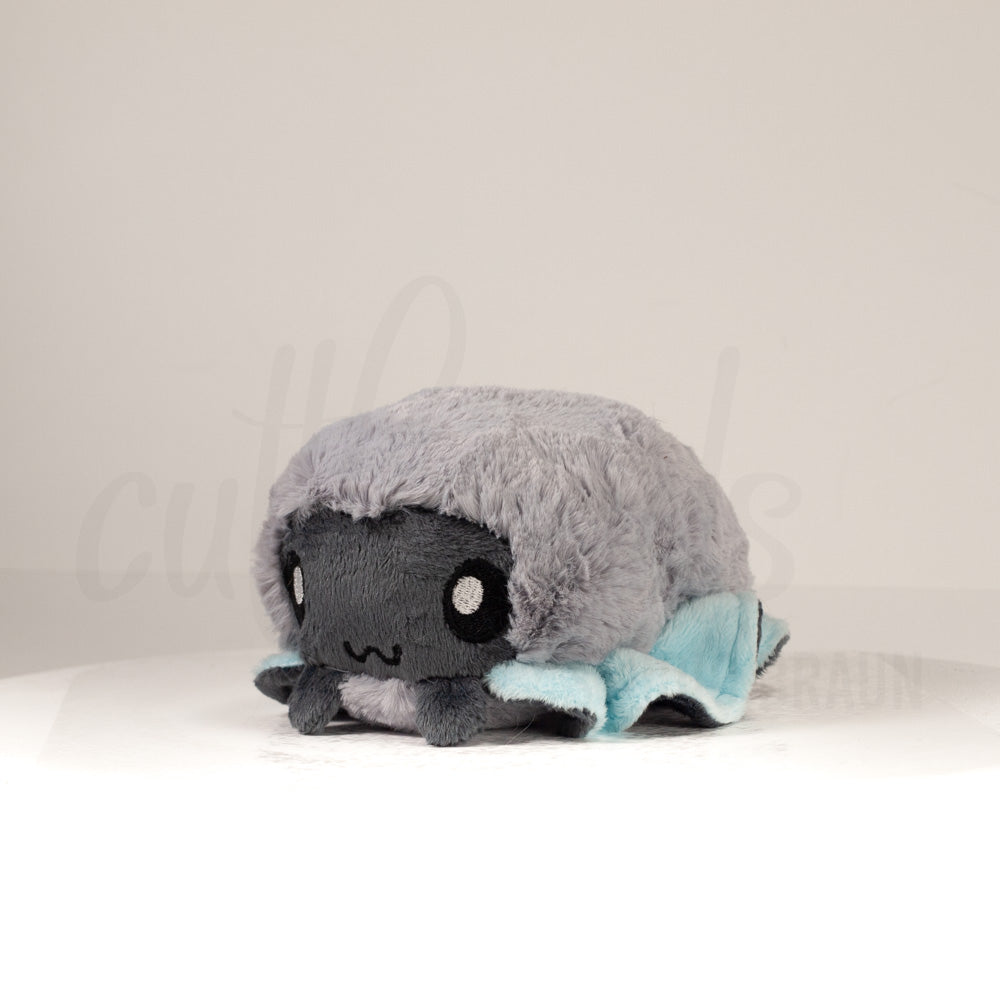 Front view of a cuttlepod plush toy, captured at a slight angle to highlight its charming features: large, cartoonish eyes, ruffled fins, and a cuddly, furry texture.