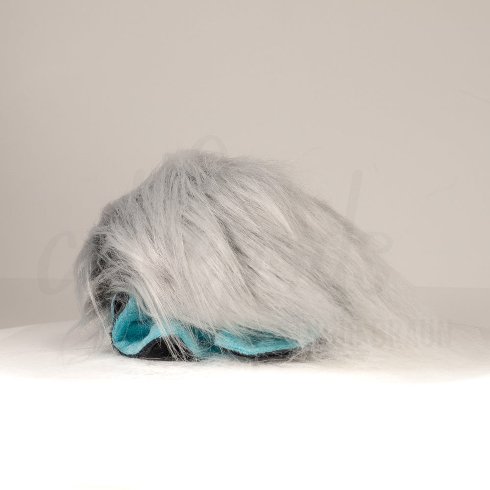 Slightly angled back view of a cuttlepod plush toy, highlighting two-tone ruffled fins, and a cuddly, furry body that comes to a soft point at the rear.