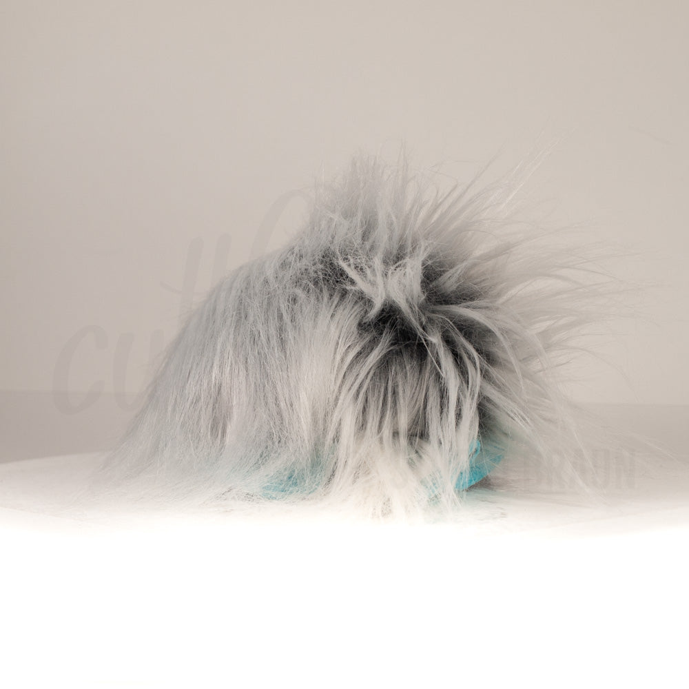 Slightly angled back view of a cuttlepod plush toy, highlighting two-tone ruffled fins, and a cuddly, furry body that comes to a soft point at the rear.