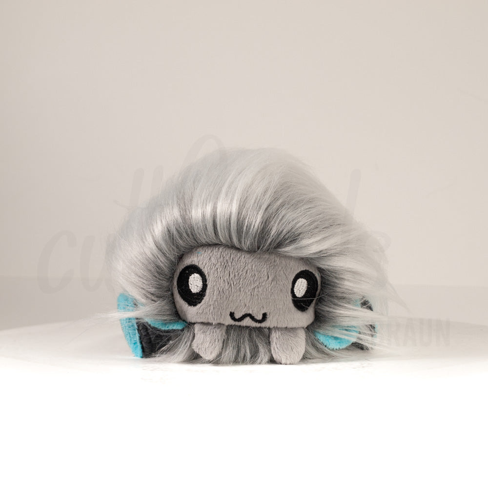 Front view of a cuttlepod plush toy, showcasing its unique form with large, cartoonish eyes, ruffled fins, and a cuddly, furry texture.