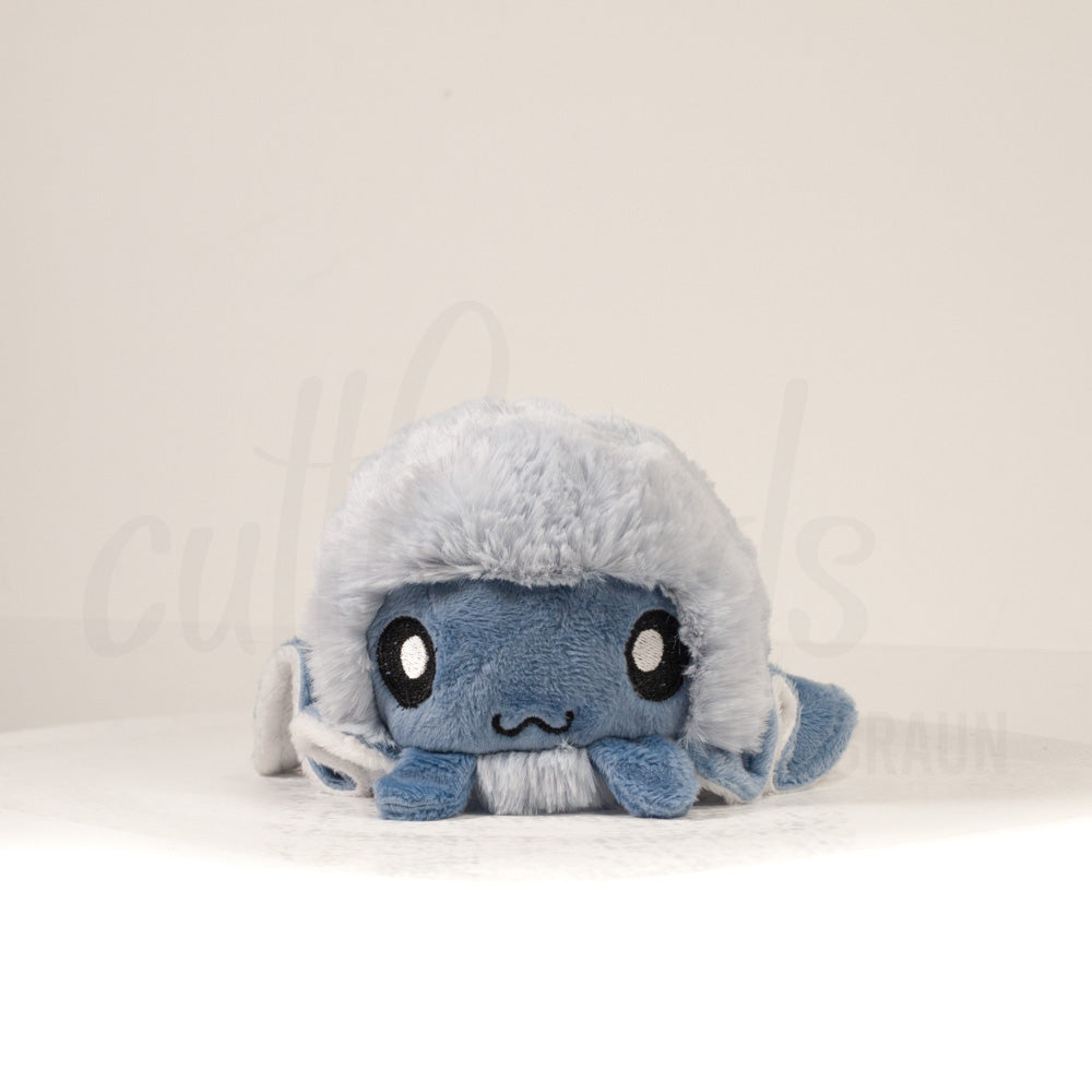 Front view of a cuttlepod plush toy, showcasing its unique form with large, cartoonish eyes, ruffled fins, and a cuddly, furry texture.