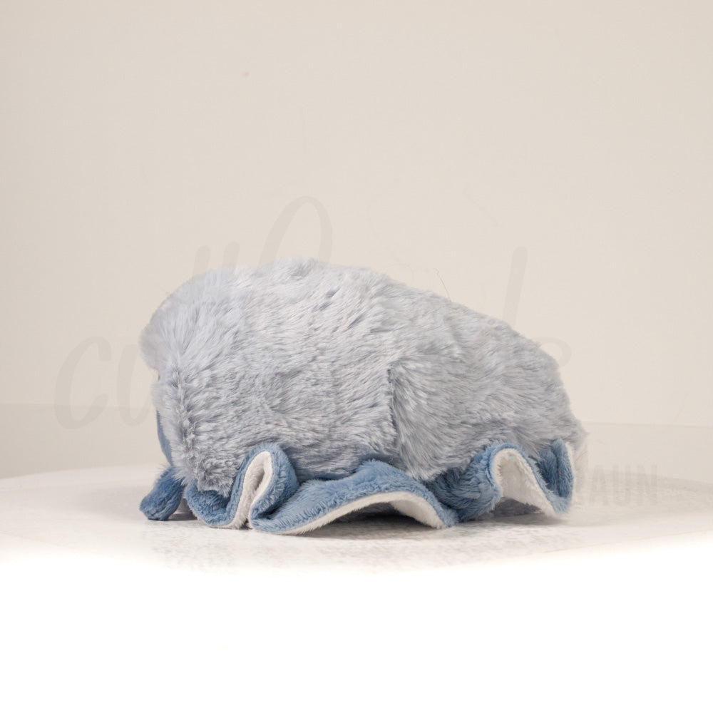 Side profile view of a cuttlepod plush toy, showcasing two-tone ruffled fins, and a cuddly, furry body.