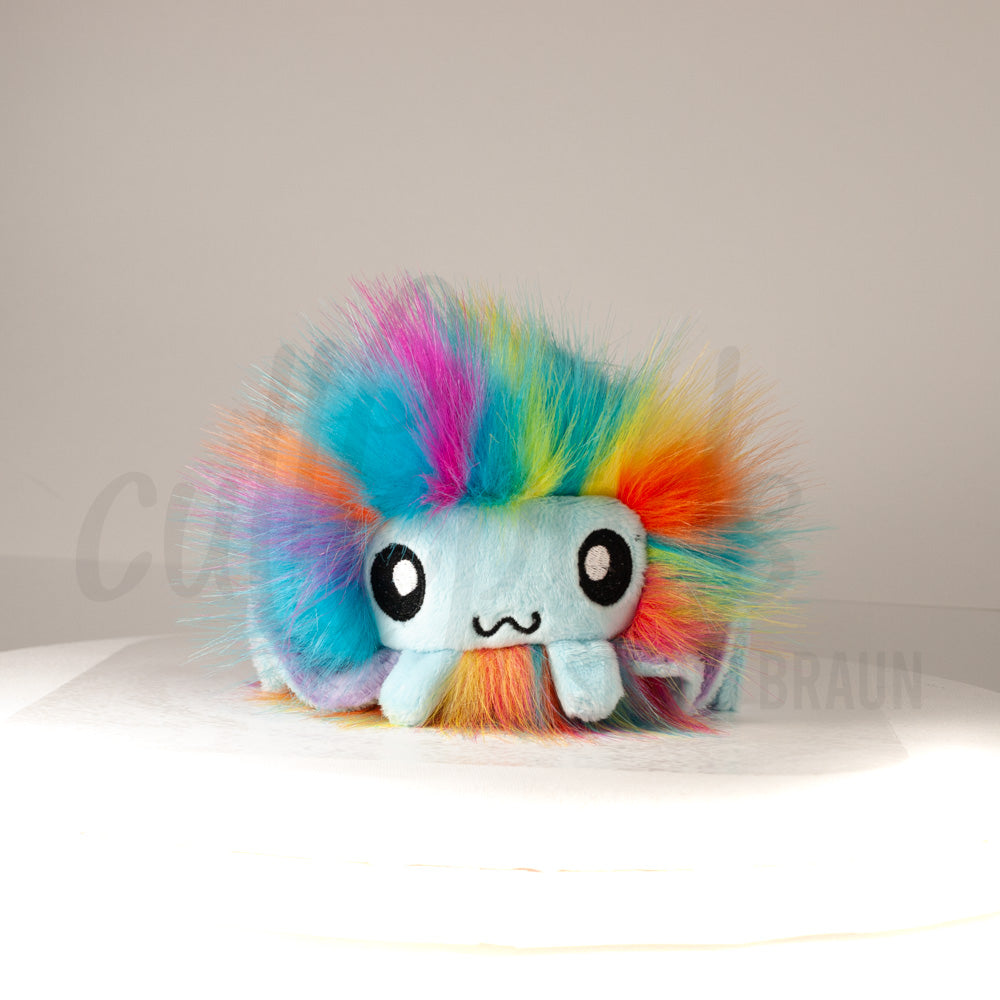 Front view of a cuttlepod plush toy, showcasing its unique form with large, cartoonish eyes, ruffled fins, and a cuddly, furry texture.