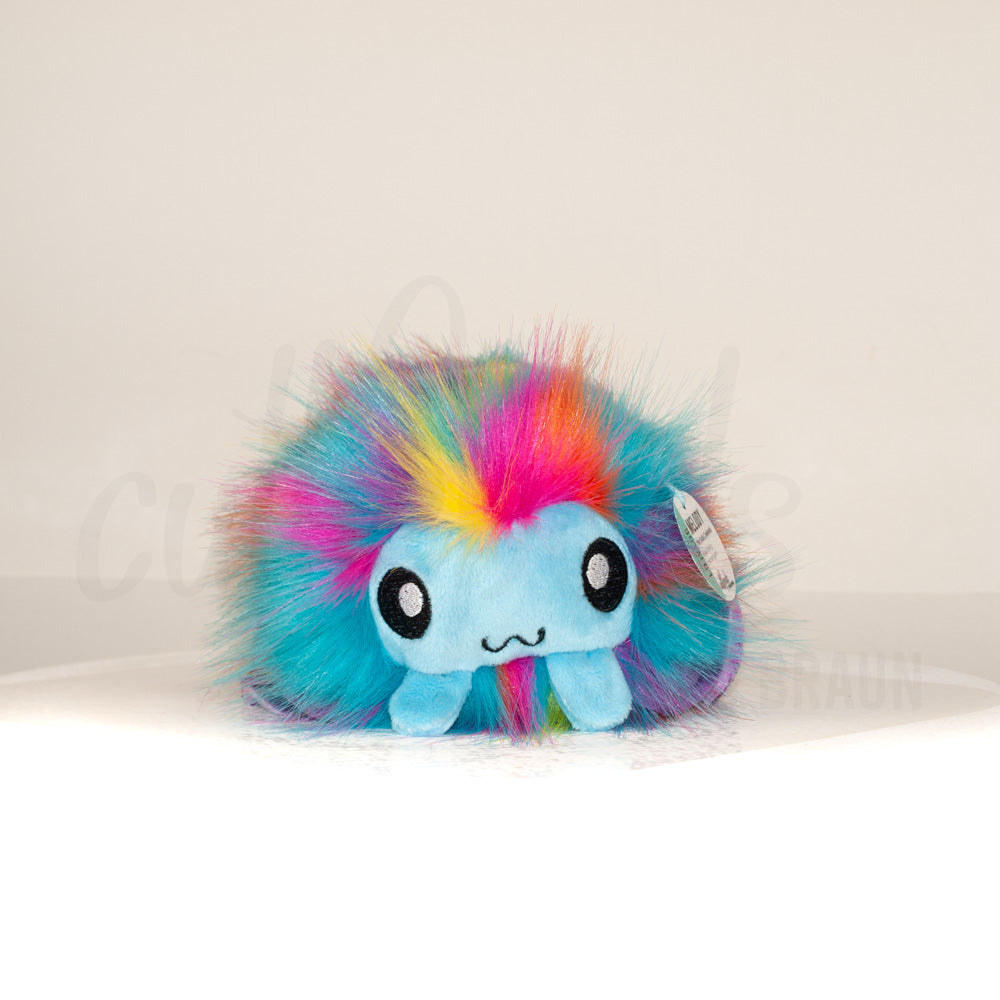 Front view of a cuttlepod plush toy, showcasing its unique form with large, cartoonish eyes, ruffled fins, and a cuddly, furry texture.