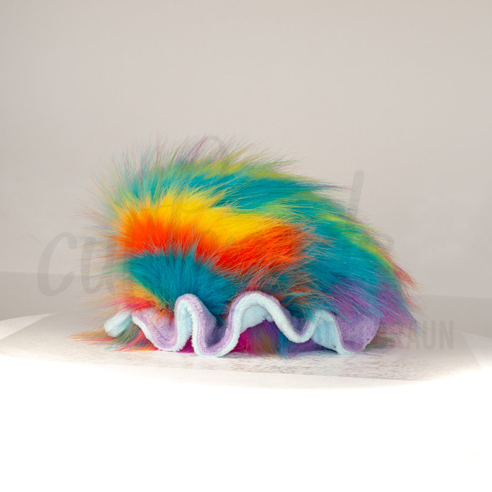 Side profile view of a cuttlepod plush toy, showcasing two-tone ruffled fins, and a cuddly, furry body.