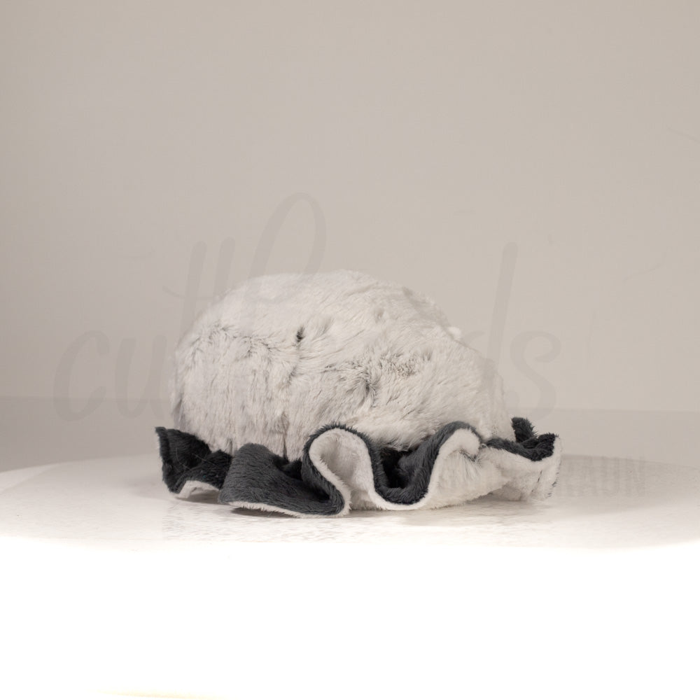 Slightly angled back view of a cuttlepod plush toy, highlighting two-tone ruffled fins, and a cuddly, furry body that comes to a soft point at the rear.