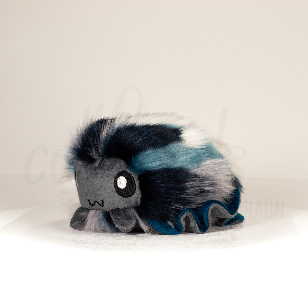 Front view of a cuttlepod plush toy, captured at a slight angle to highlight its charming features: large, cartoonish eyes, ruffled fins, and a cuddly, furry texture.