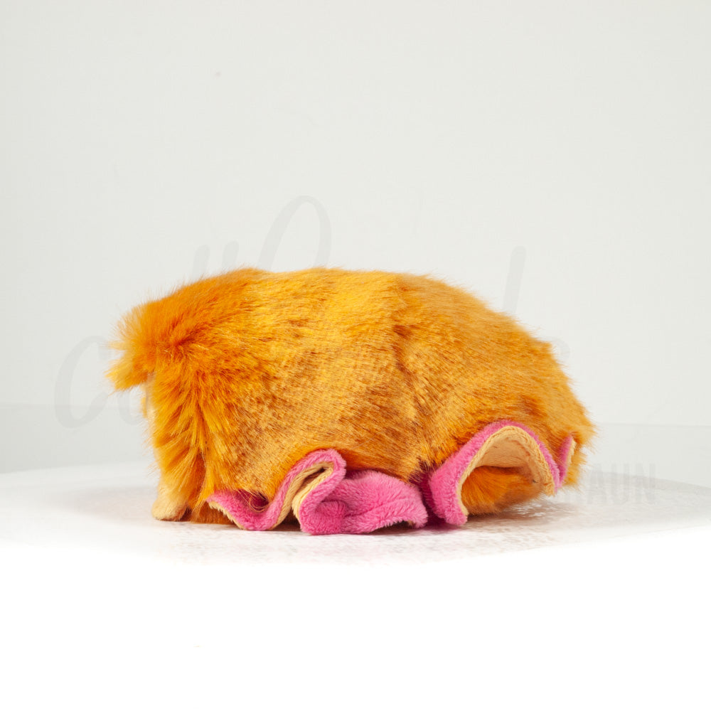 Side profile view of a cuttlepod plush toy, showcasing two-tone ruffled fins, and a cuddly, furry body.