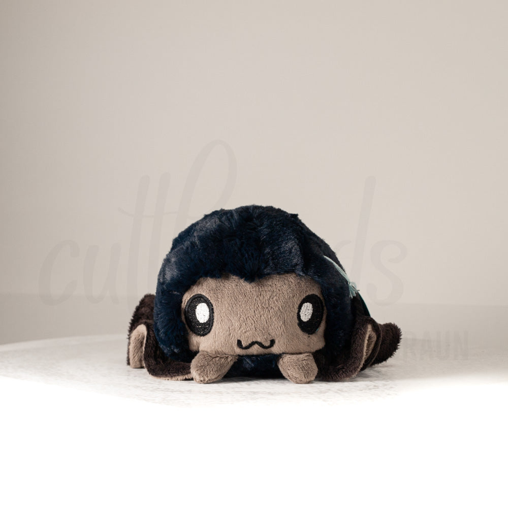 Front view of a cuttlepod plush toy, showcasing its unique form with large, cartoonish eyes, ruffled fins, and a cuddly, furry texture.