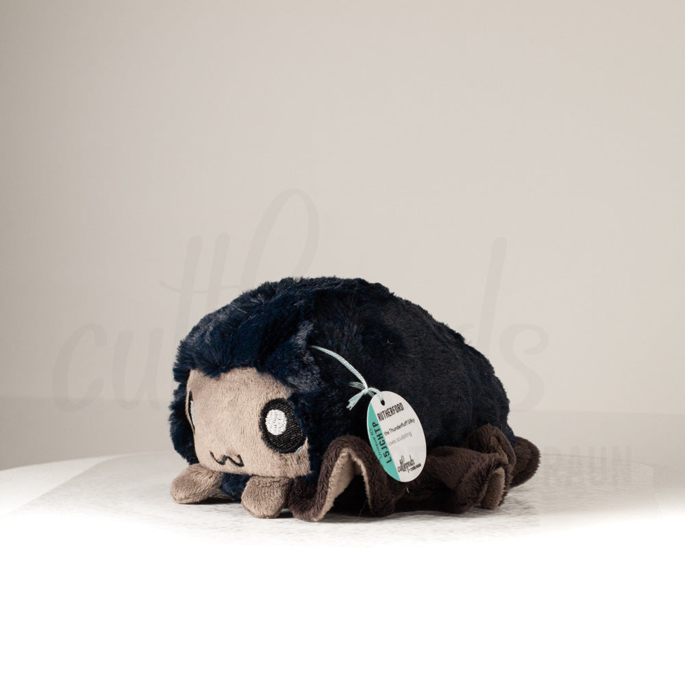 Front view of a cuttlepod plush toy, captured at a slight angle to highlight its charming features: large, cartoonish eyes, ruffled fins, and a cuddly, furry texture.