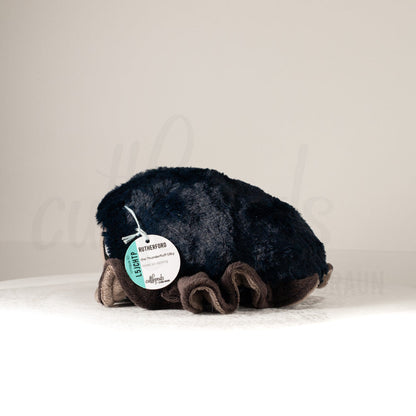 Side profile view of a cuttlepod plush toy, showcasing two-tone ruffled fins, and a cuddly, furry body.