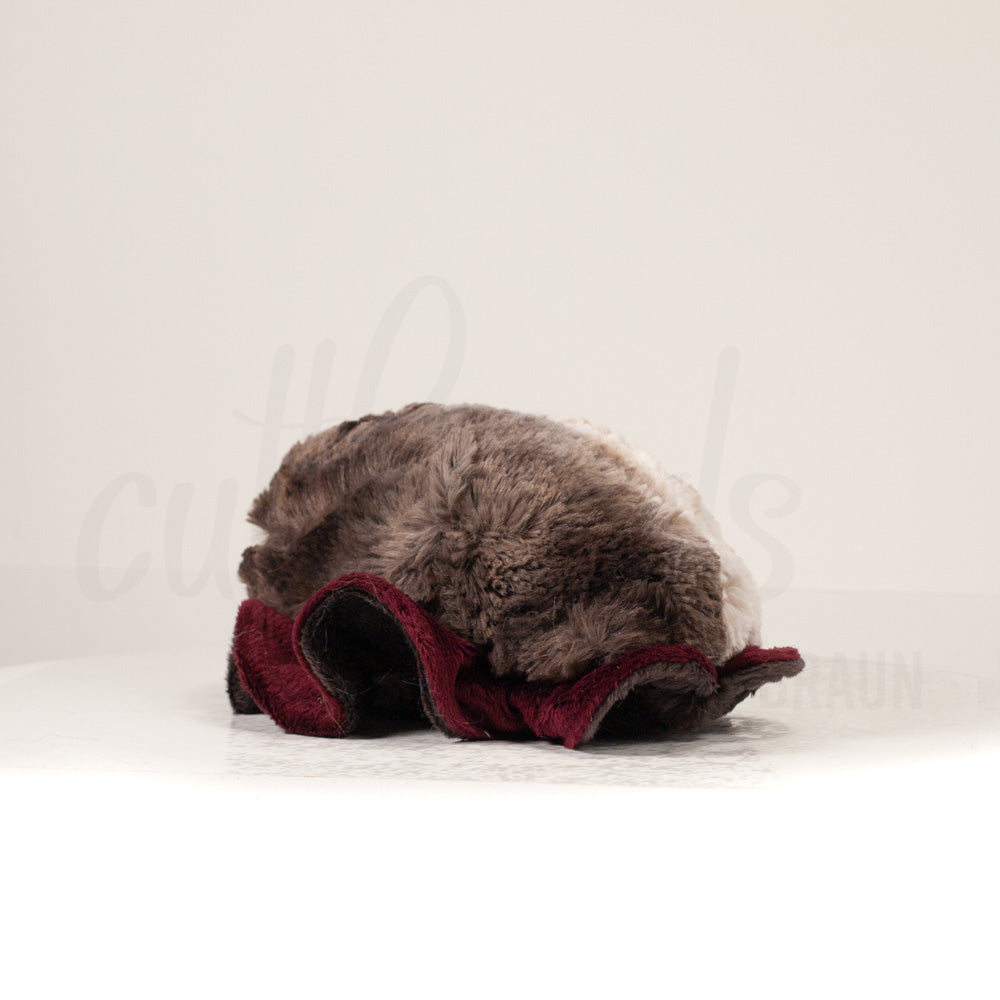 Slightly angled back view of a cuttlepod plush toy, highlighting two-tone ruffled fins, and a cuddly, furry body that comes to a soft point at the rear.