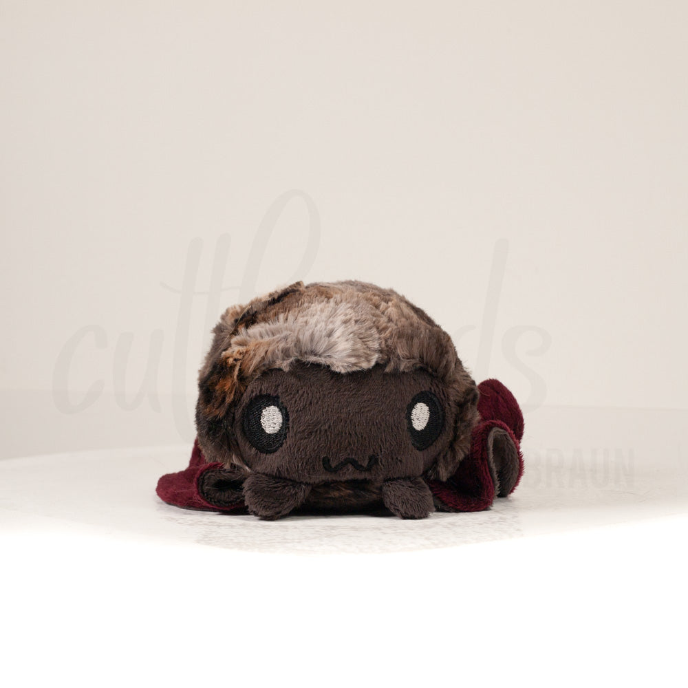 Front view of a cuttlepod plush toy, showcasing its unique form with large, cartoonish eyes, ruffled fins, and a cuddly, furry texture.