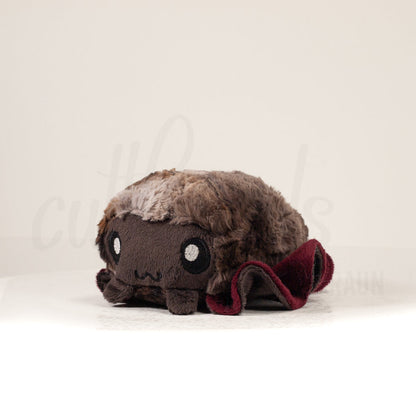 Front view of a cuttlepod plush toy, captured at a slight angle to highlight its charming features: large, cartoonish eyes, ruffled fins, and a cuddly, furry texture.