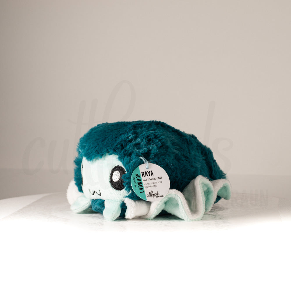 Front view of a cuttlepod plush toy, captured at a slight angle to highlight its charming features: large, cartoonish eyes, ruffled fins, and a cuddly, furry texture.