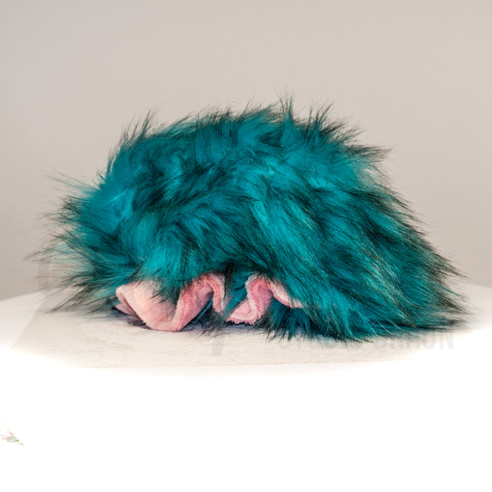 Slightly angled back view of a cuttlepod plush toy, highlighting two-tone ruffled fins, and a cuddly, furry body that comes to a soft point at the rear.