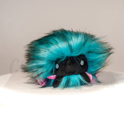 Front view of a cuttlepod plush toy, showcasing its unique form with large, cartoonish eyes, ruffled fins, and a cuddly, furry texture.