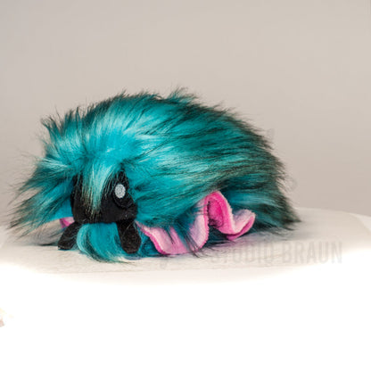 Front view of a cuttlepod plush toy, captured at a slight angle to highlight its charming features: large, cartoonish eyes, ruffled fins, and a cuddly, furry texture.