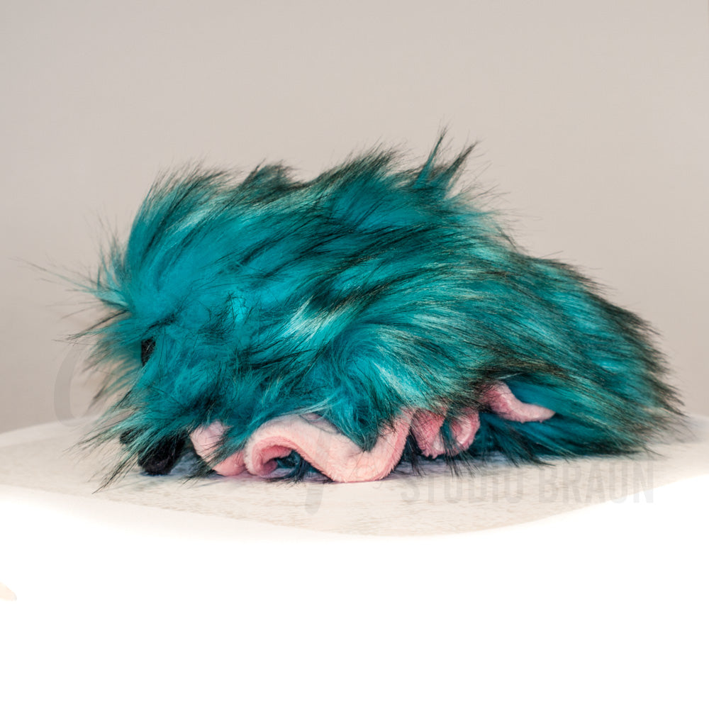 Side profile view of a cuttlepod plush toy, showcasing two-tone ruffled fins, and a cuddly, furry body.