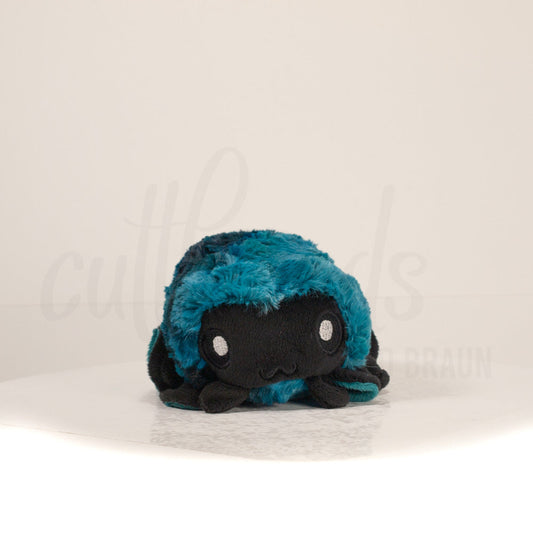 Front view of a cuttlepod plush toy, showcasing its unique form with large, cartoonish eyes, ruffled fins, and a cuddly, furry texture.