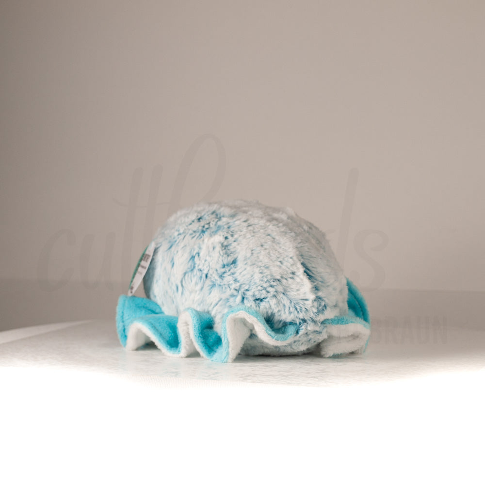 Slightly angled back view of a cuttlepod plush toy, highlighting two-tone ruffled fins, and a cuddly, furry body that comes to a soft point at the rear.