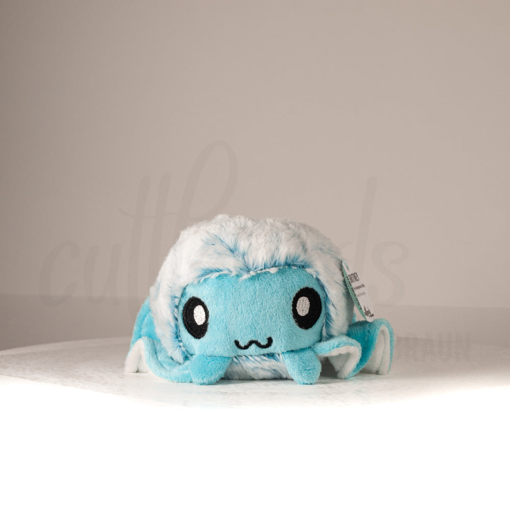 Front view of a cuttlepod plush toy, showcasing its unique form with large, cartoonish eyes, ruffled fins, and a cuddly, furry texture.