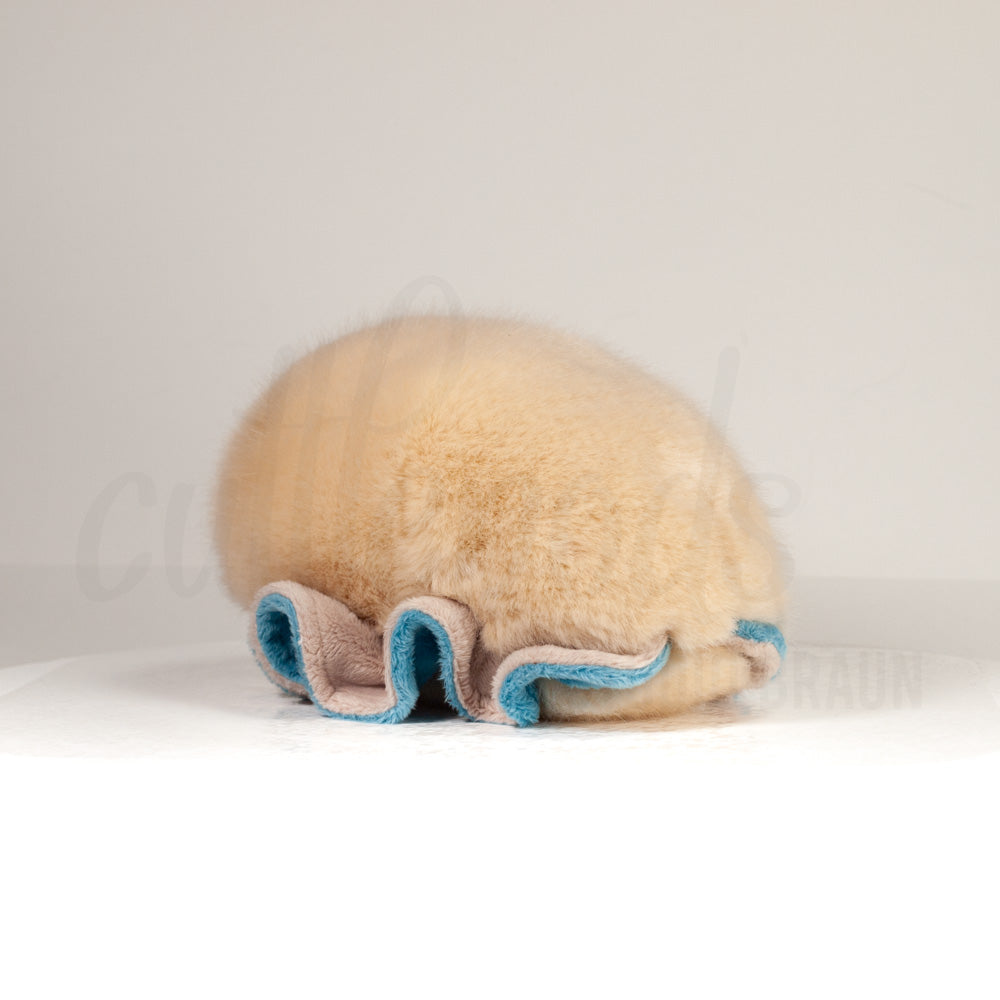 Slightly angled back view of a cuttlepod plush toy, highlighting two-tone ruffled fins, and a cuddly, furry body that comes to a soft point at the rear.