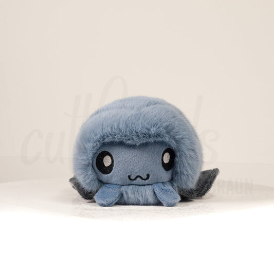 Front view of a cuttlepod plush toy, showcasing its unique form with large, cartoonish eyes, ruffled fins, and a cuddly, furry texture.