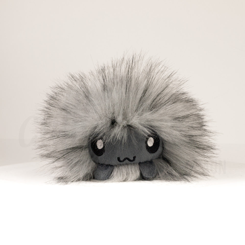 Front view of a cuttlepod plush toy, showcasing its unique form with large, cartoonish eyes, ruffled fins, and a cuddly, furry texture.