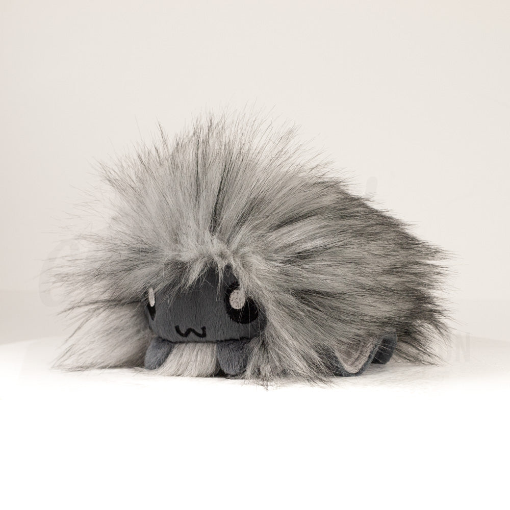 Front view of a cuttlepod plush toy, captured at a slight angle to highlight its charming features: large, cartoonish eyes, ruffled fins, and a cuddly, furry texture.