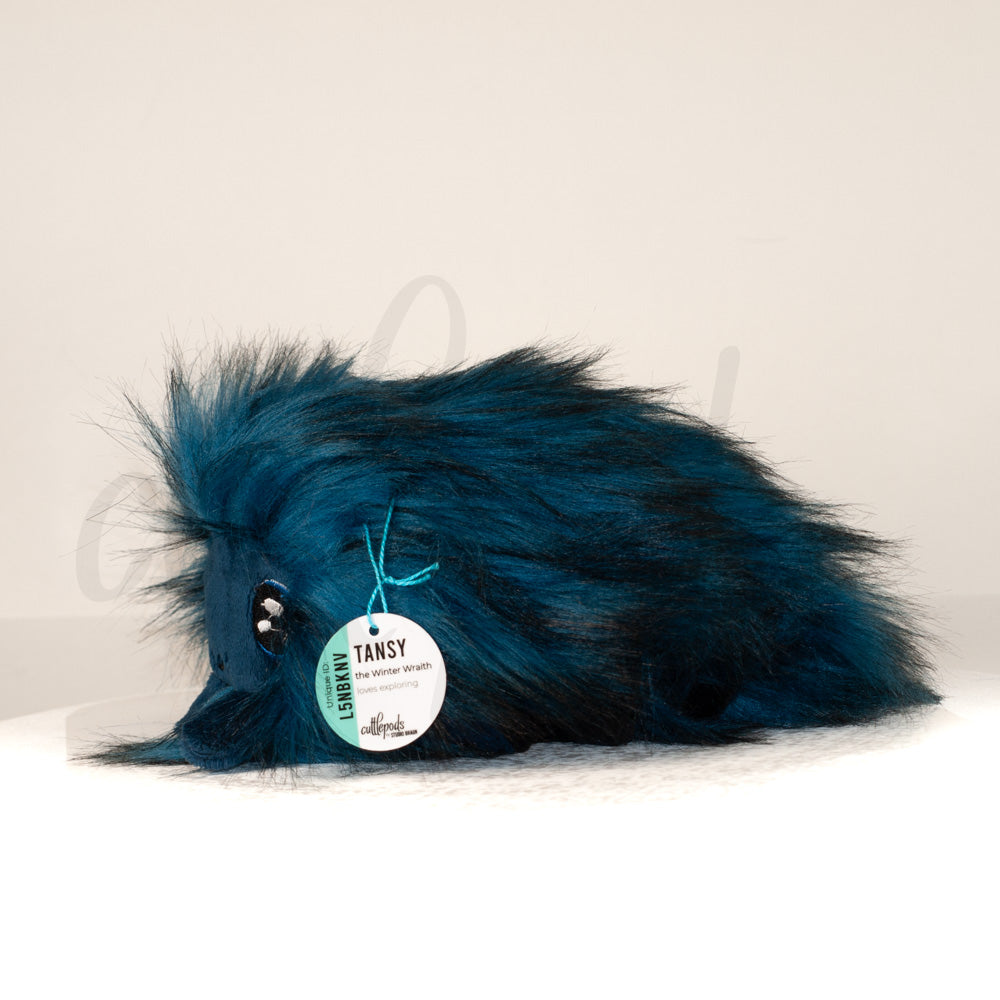 Side profile view of a cuttlepod plush toy, showcasing two-tone ruffled fins, and a cuddly, furry body.