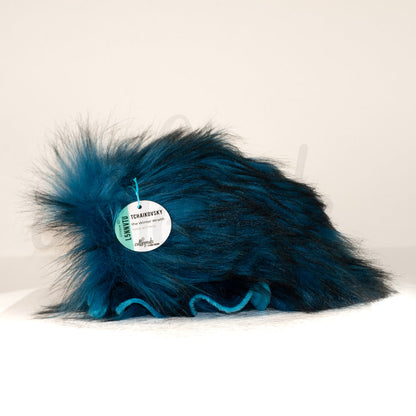 Side profile view of a cuttlepod plush toy, showcasing two-tone ruffled fins, and a cuddly, furry body.