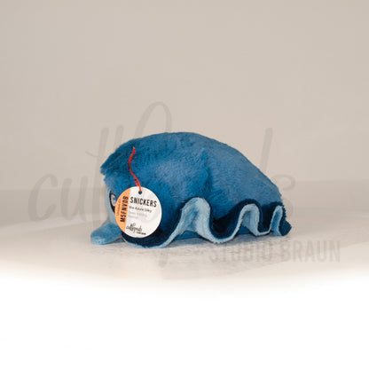 Side profile view of a cuttlepod plush toy, showcasing two-tone ruffled fins, and a cuddly, furry body.