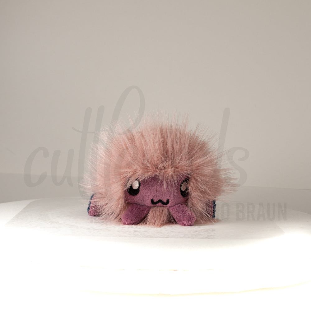 Front view of a cuttlepod plush toy, showcasing its unique form with large, cartoonish eyes, ruffled fins, and a cuddly, furry texture.