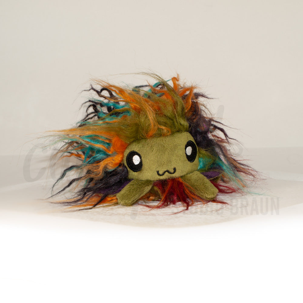 Front view of a cuttlepod plush toy, showcasing its unique form with large, cartoonish eyes, ruffled fins, and a cuddly, furry texture.