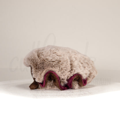 Side profile view of a cuttlepod plush toy, showcasing two-tone ruffled fins, and a cuddly, furry body.