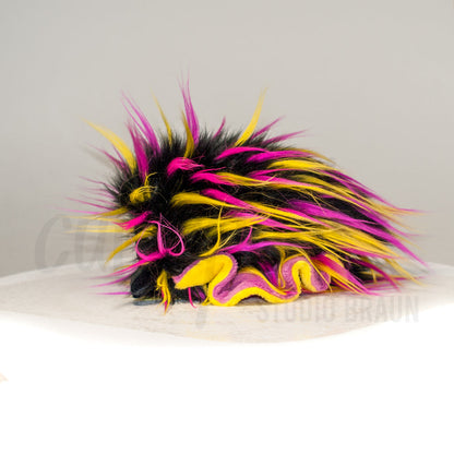 Side profile view of a cuttlepod plush toy, showcasing two-tone ruffled fins, and a cuddly, furry body.