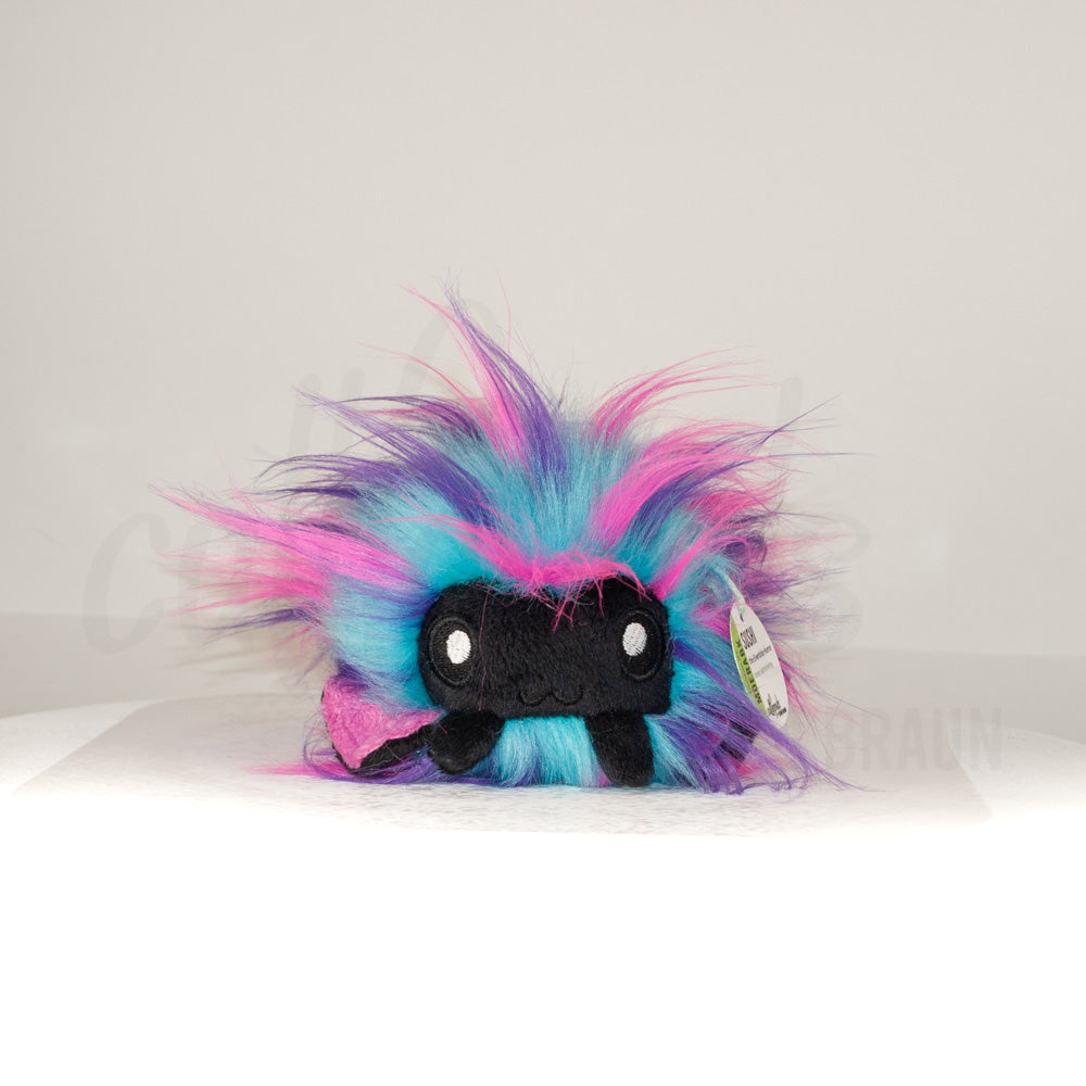 Front view of a cuttlepod plush toy, showcasing its unique form with large, cartoonish eyes, ruffled fins, and a cuddly, furry texture.