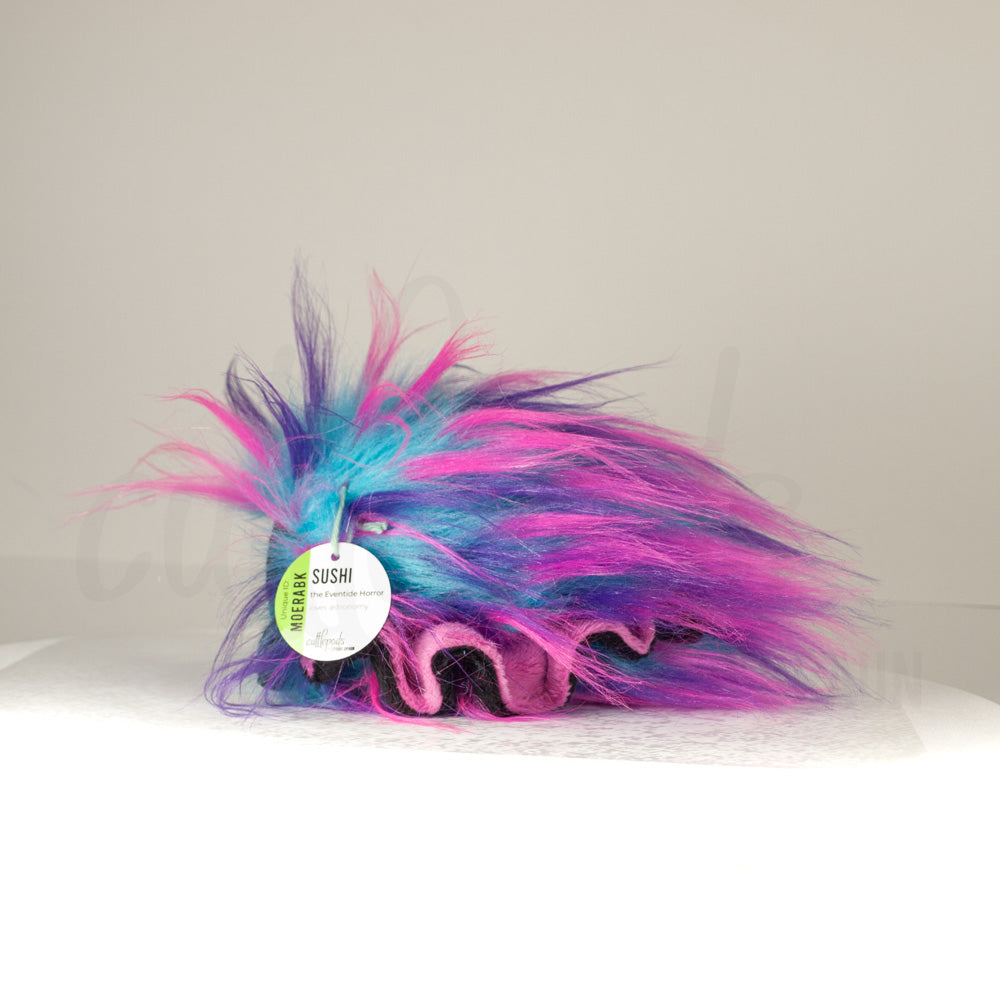 Side profile view of a cuttlepod plush toy, showcasing two-tone ruffled fins, and a cuddly, furry body.