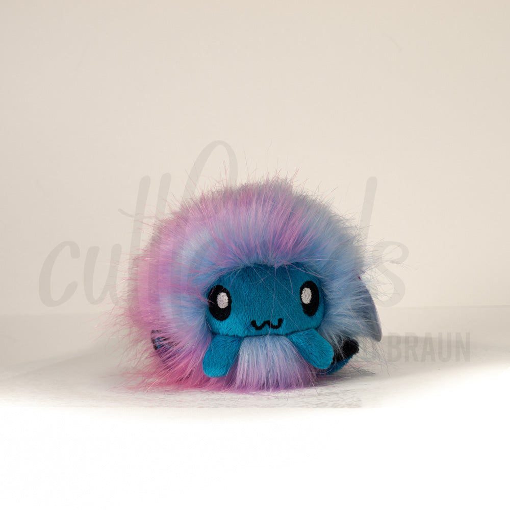 Front view of a cuttlepod plush toy, showcasing its unique form with large, cartoonish eyes, ruffled fins, and a cuddly, furry texture.