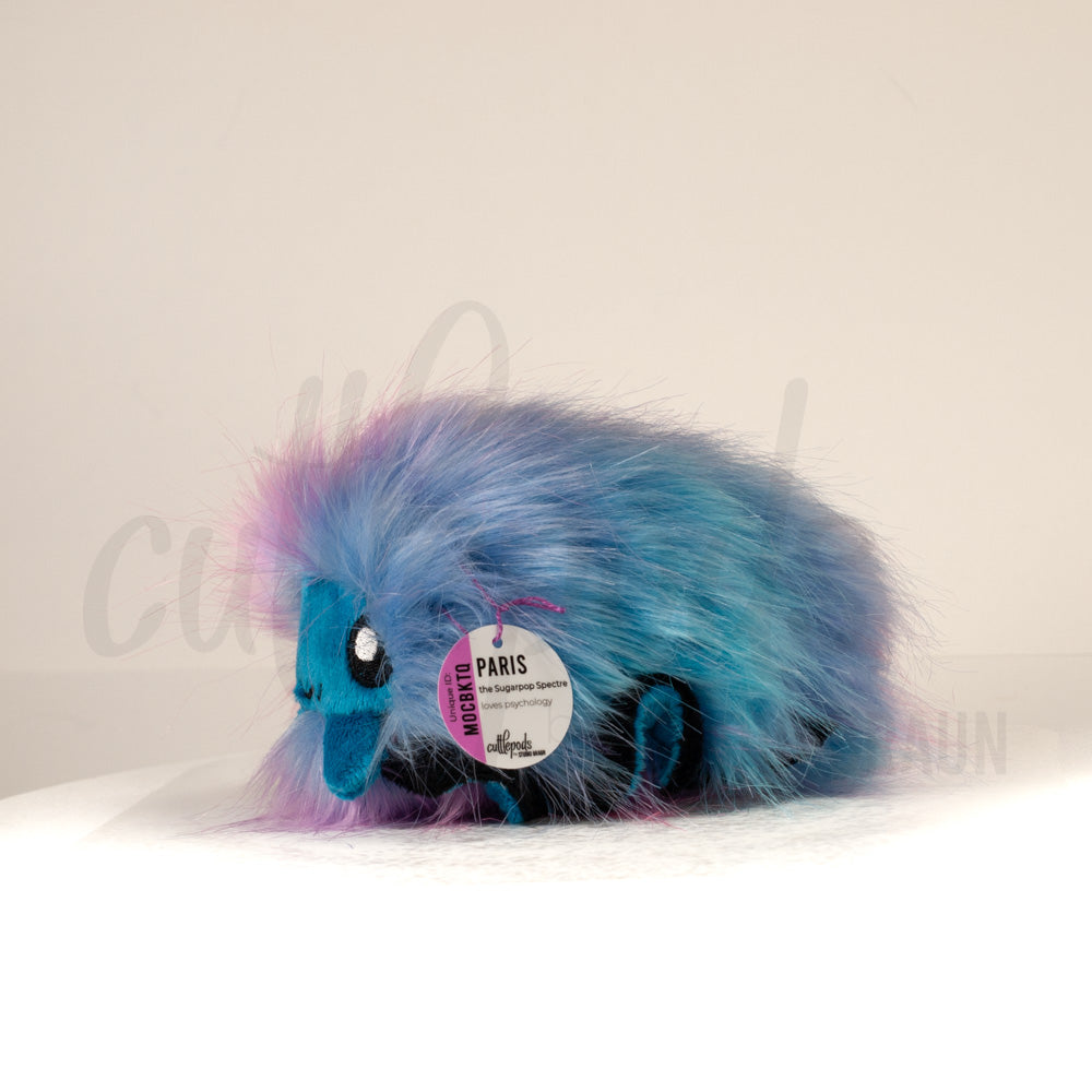 Side profile view of a cuttlepod plush toy, showcasing two-tone ruffled fins, and a cuddly, furry body.