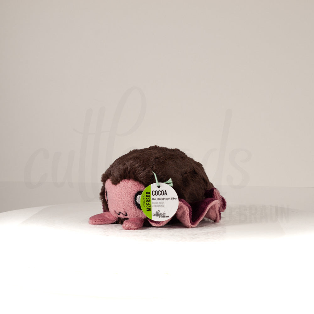 Front view of a cuttlepod plush toy, captured at a slight angle to highlight its charming features: large, cartoonish eyes, ruffled fins, and a cuddly, furry texture.