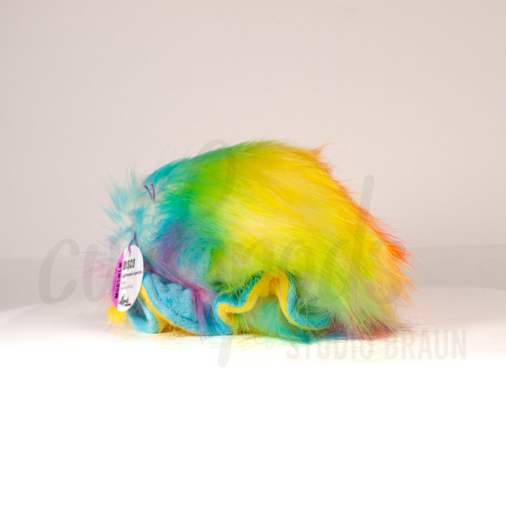 Slightly angled back view of a cuttlepod plush toy, highlighting two-tone ruffled fins, and a cuddly, furry body that comes to a soft point at the rear.