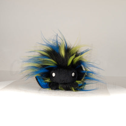 Front view of a cuttlepod plush toy, showcasing its unique form with large, cartoonish eyes, ruffled fins, and a cuddly, furry texture.