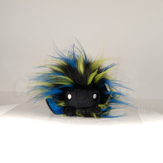 Front view of a cuttlepod plush toy, showcasing its unique form with large, cartoonish eyes, ruffled fins, and a cuddly, furry texture.