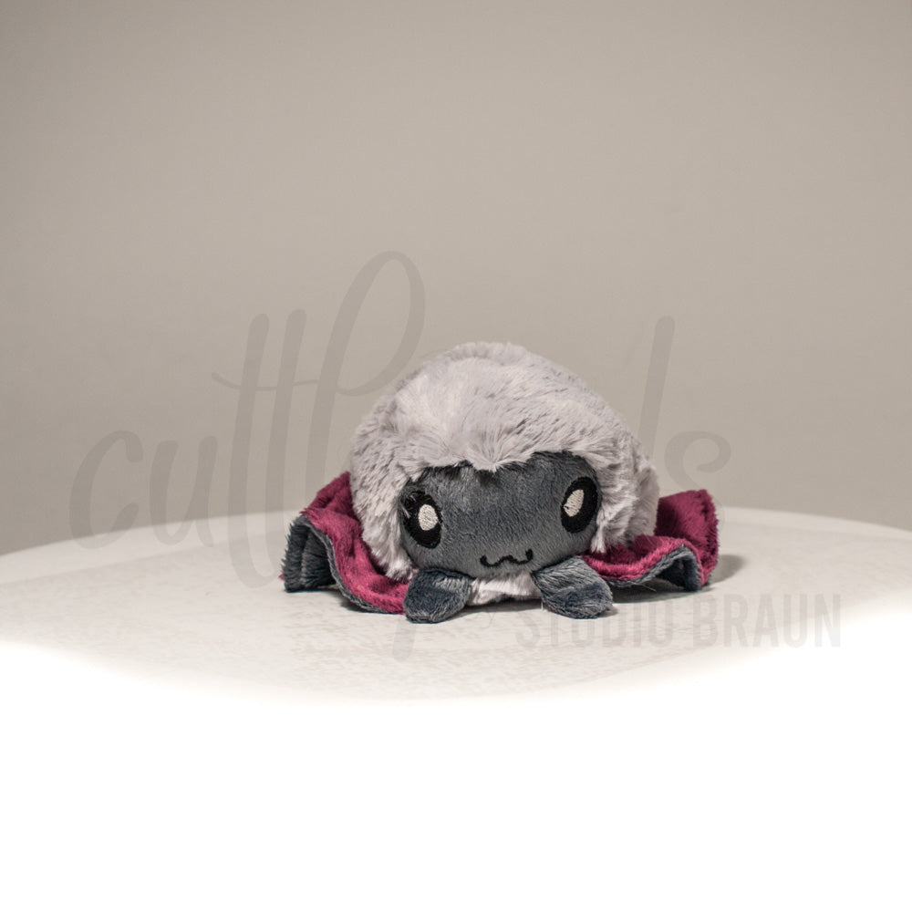 Front view of a cuttlepod plush toy, showcasing its unique form with large, cartoonish eyes, ruffled fins, and a cuddly, furry texture.