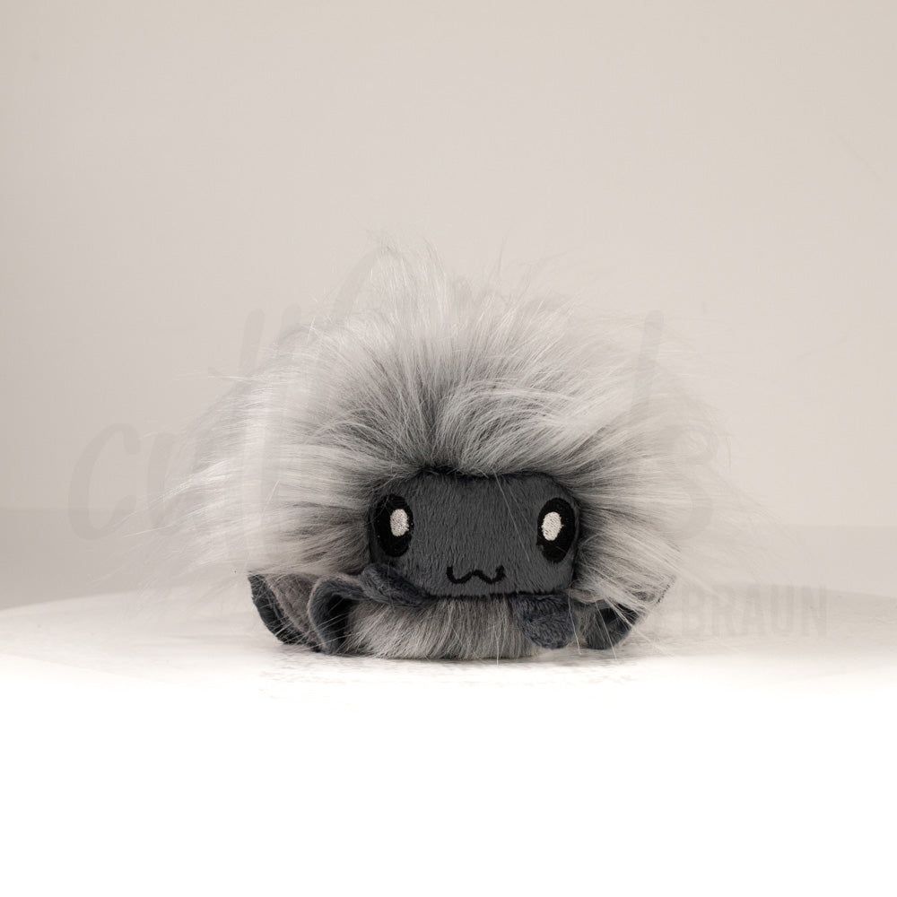 Front view of a cuttlepod plush toy, showcasing its unique form with large, cartoonish eyes, ruffled fins, and a cuddly, furry texture.